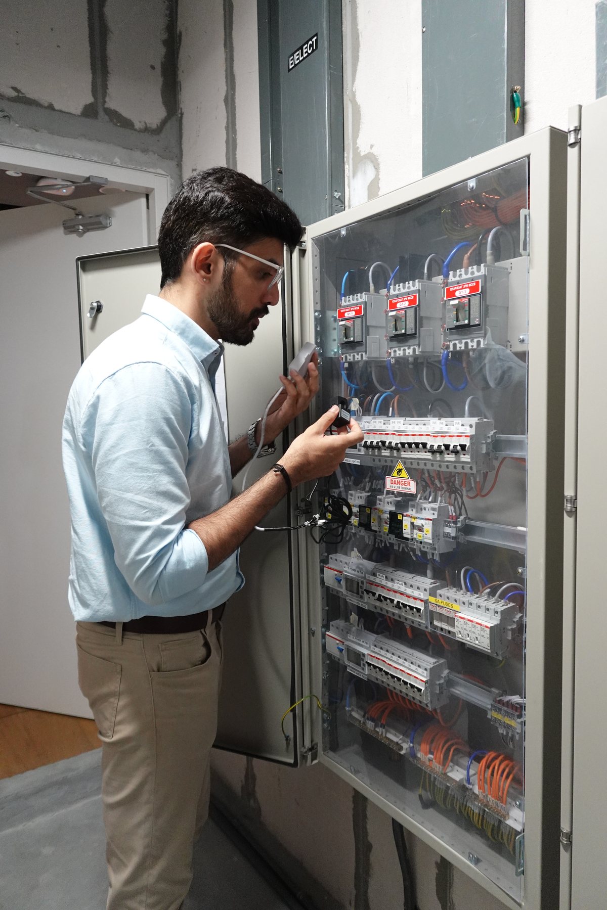 An electrician clamping a sensor kit inside a live panel